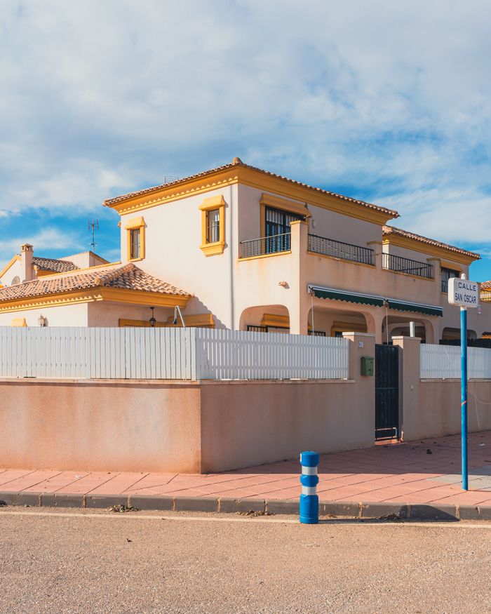 Charming Mediterranean-style house on a sunlit street corner.